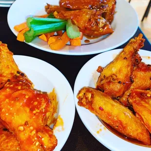 three plates of wings and vegetables