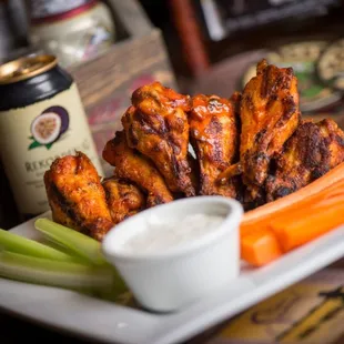 a plate of buffalo wings with celery and carrots