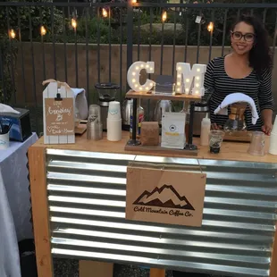 a woman behind a cold mountain coffee station