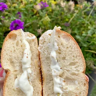 a hand holding a bagel with a bite taken out of it
