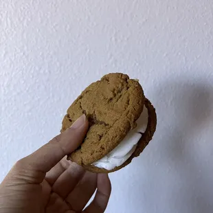 a hand holding a cookie with cream filling