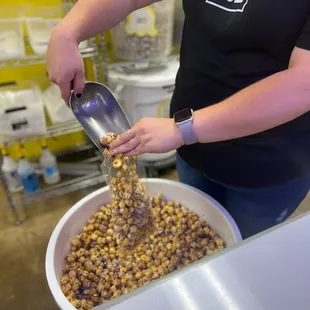 a woman scooping peanuts into a bowl