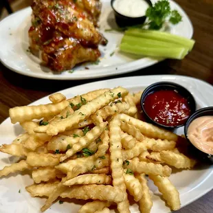 a plate of french fries and a plate of chicken wings