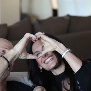 a man and a woman making a heart with their hands