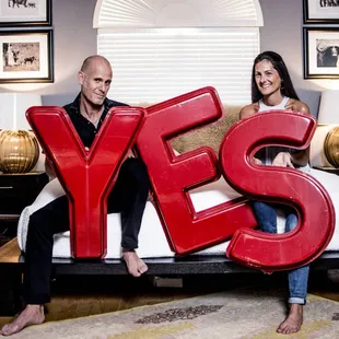 a man and a woman sitting on a couch holding a yes sign