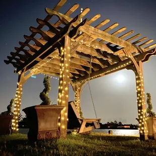 The gazebo / porch swing that overlooks the water at night with a full moon.