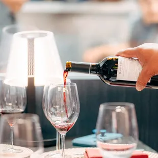 a person pouring wine into a glass