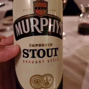 a person holding a bottle of murphy's stout