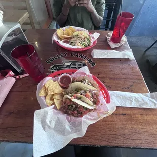 closer end: 3 Shredded Chicken Tacos,  far side: 3 beef tacos, 2 sides of chips
