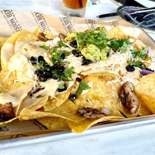 Sheet Tray Nacos of blackened chicken, cabbage, black bean mango salsa, beer cheese, cilantro, avocado