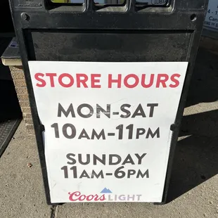 a store hours sign on a sidewalk