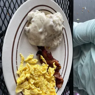 a plate of eggs, bacon and mashed potatoes