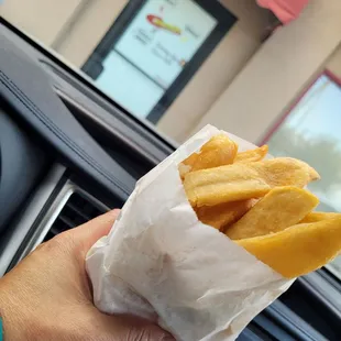  a hand holding a bag of fries