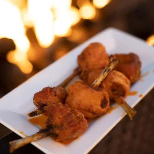 a plate of chicken skewers with a fire in the background