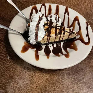 a slice of cheesecake with chocolate sauce and whipped cream