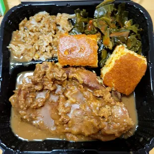 smothered pork chop with greens , rice and gravy and corn bread.   This is definitely not a pork chop this is  Is a pork steak.