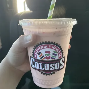 a hand holding a pink drink