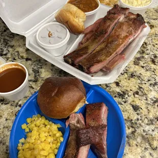 a plate of ribs, corn, and a roll