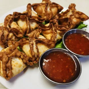 a plate of dumplings with dipping sauces