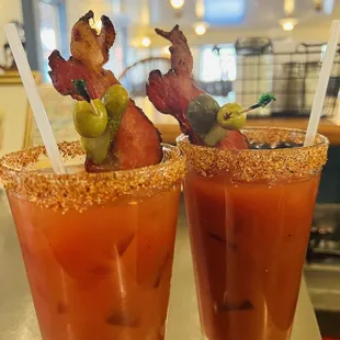 two bloody drinks with bacon and olives