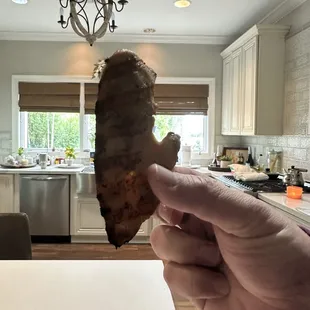 a hand holding a piece of meat