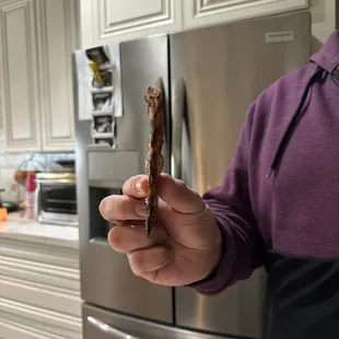 a man holding a piece of bacon