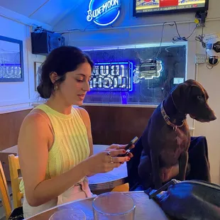 a woman sitting at a table with a dog