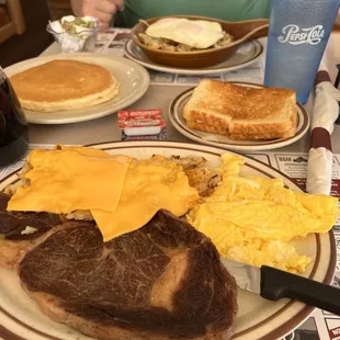Ribeye steak, scrambled eggs, hash browns with onion and cheese and sourdough toast.  Pancake and meat skillet with eggs over easy.