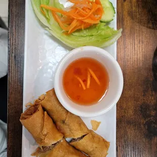 a plate of vegetable spring rolls and a bowl of dipping sauce