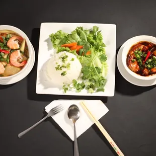 a plate of rice, shrimp, and vegetables with chopsticks
