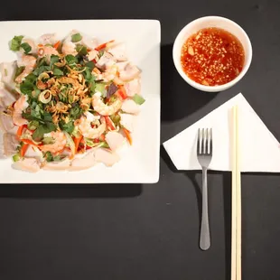 a plate of food with chopsticks and a bowl of sauce