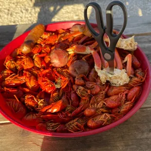 a bowl of crawfish with a pair of scissors