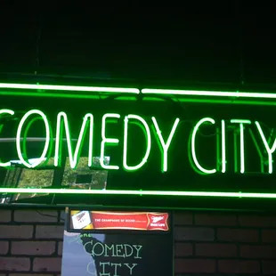 a neon sign that reads comedy city