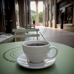 Pour over cup of coffee, on a table in the arcade.