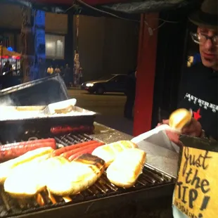 a man cooking hot dogs on a grill