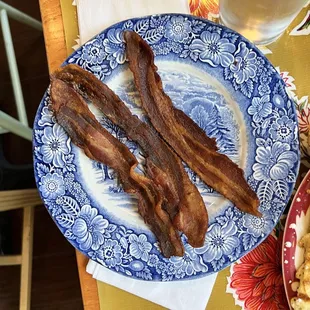 bacon and pancakes on a blue and white plate