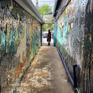 a man walking down an alley with graffiti on the walls