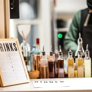 a man standing behind a counter with bottles of alcohol