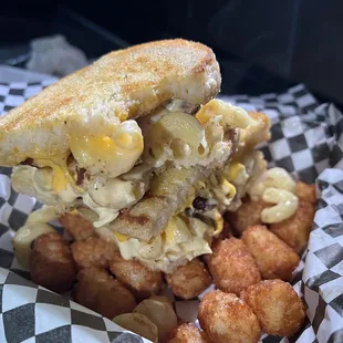 Bacon Mac-daddy. Grilled cheese on sourdough stuffed with bacon Mac-n-cheese over tots 100% fire!!