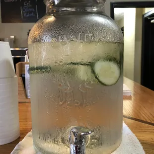 a beverage dispenser with cucumbers in it