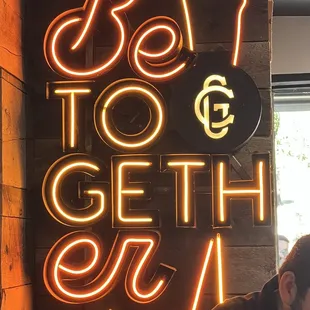 a man sitting in front of a neon sign