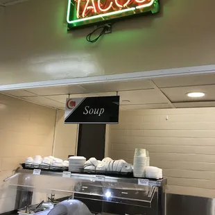a neon taco's sign above the counter