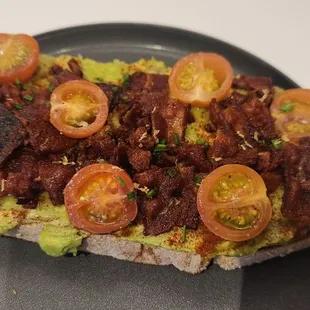 a toast with bacon, tomatoes, and avocado