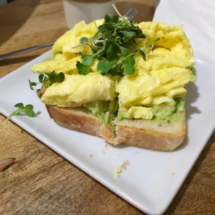 Avocado toast w/micro greens, add scrambled egg, minus chili flakes. ALOT of avocado hiding.  Bread lightly toasted to perfection.