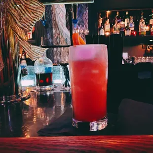 a cocktail on a bar with bottles in the background