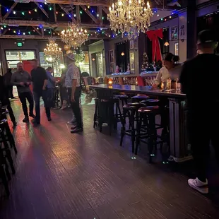 people in a bar with a chandelier hanging from the ceiling