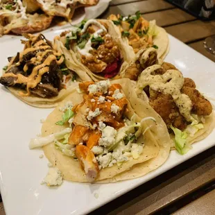 Shareable tacos- top left to right pork barn mi, tika taco, honey sriracha bottom left to right- buffalo chicken, po' boy