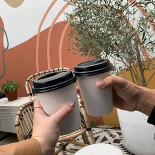 two people holding cups of coffee