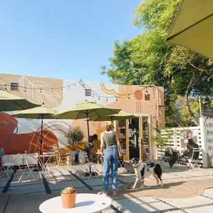 a man walking his dog in front of an outdoor cafe