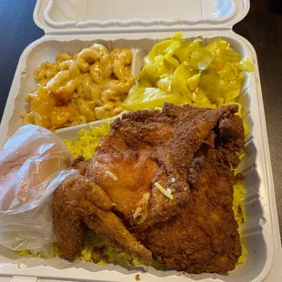 Fried chicken dinner with rice, cabbage, macaroni &amp; cheese and a roll.